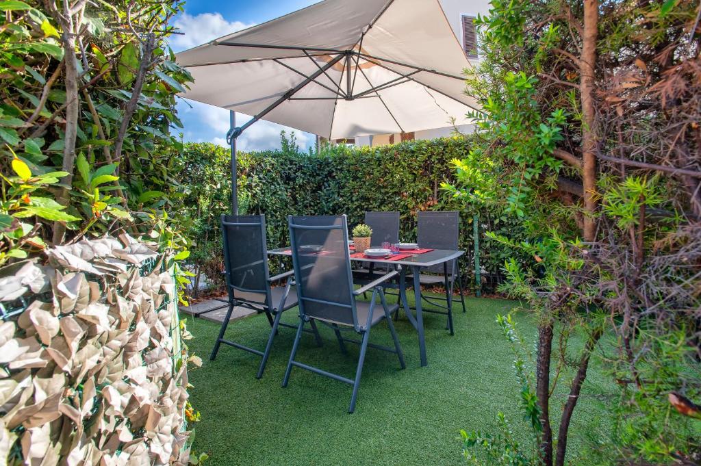 a table and chairs with an umbrella in a garden at Gio's Apartment in Castelsardo