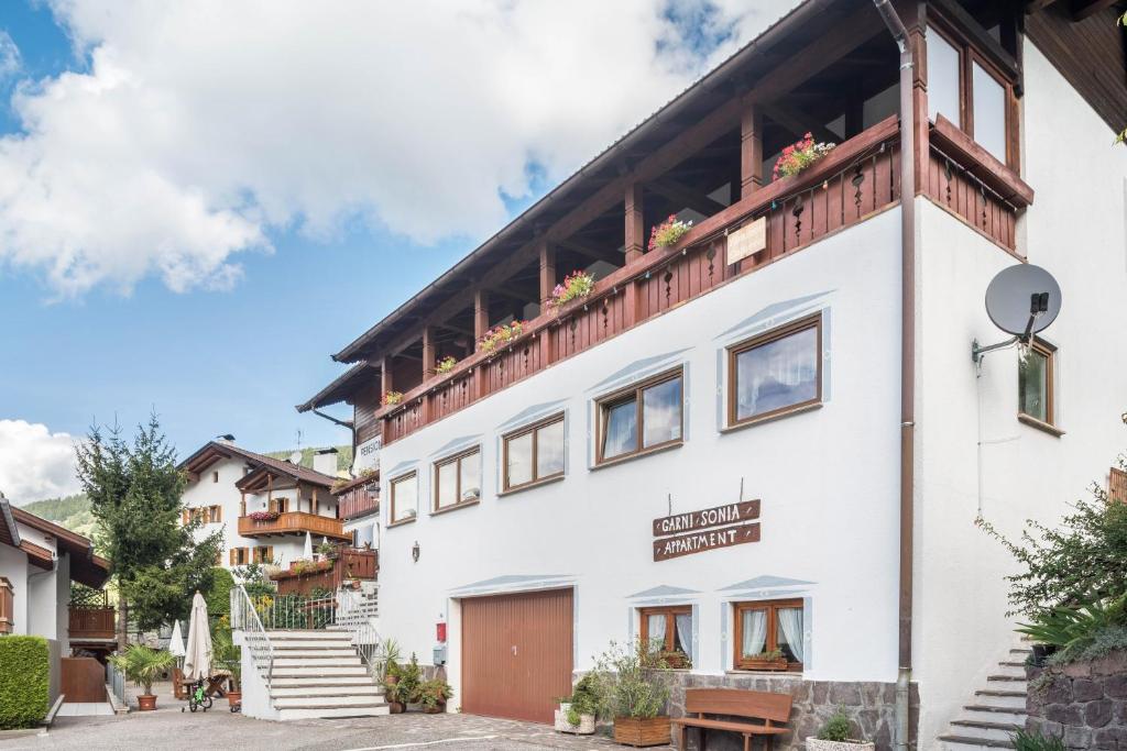 a white building with flowers on the balcony at Pension Sonia App 103 in Funes