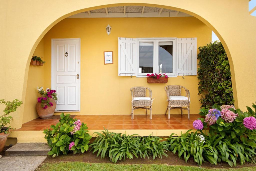 a house with two chairs and a window and flowers at Casa da Ria 78 - Family House in Torreira