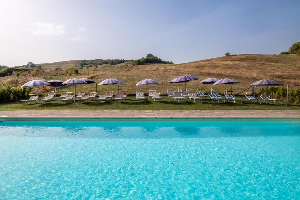 a group of chairs and umbrellas next to a pool at Ginestra in Arcidosso