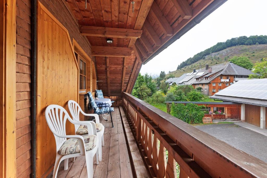 a balcony of a cabin with white chairs on it at Ferienwohnung Schweizer in Bernau im Schwarzwald