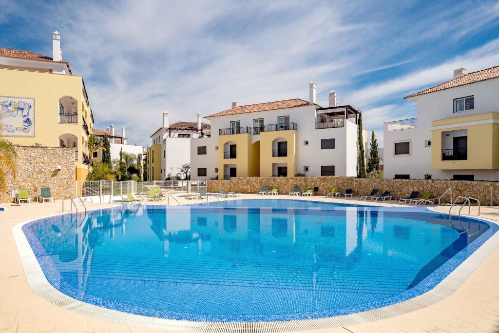 a large blue swimming pool in front of some buildings at Cosy Two Bedroom Apartment in Cabaços