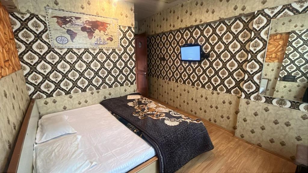 a small bed in a room with a wall at R Krishna Hotel in Srinagar