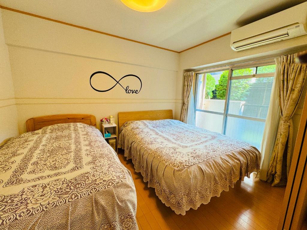 a bedroom with two beds and a window at HOTEL k&m in Tokyo
