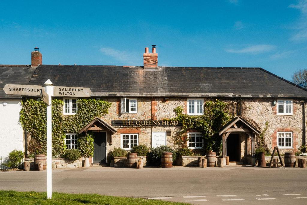an old brick building with a street sign in front of it at The Queen's Head in Broad Chalke
