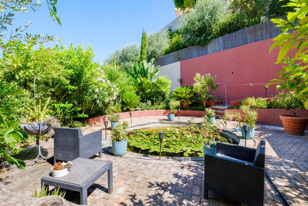 a patio with chairs and a pond with plants at Sous L'olivier in Menton