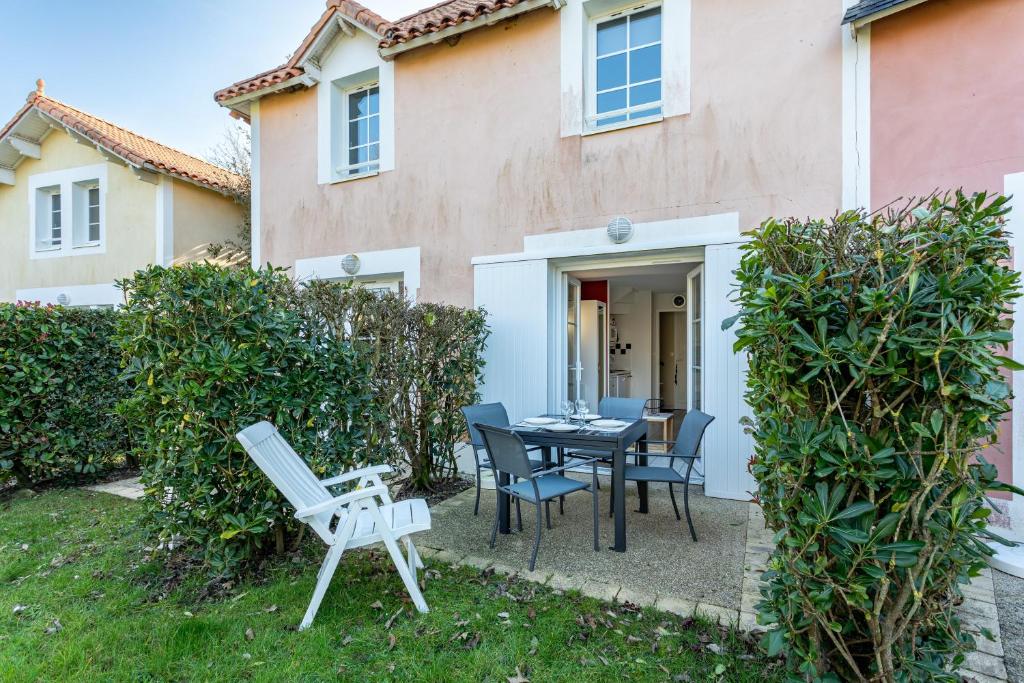 a patio with a table and chairs in front of a house at Maison Village Port-Bourgenay in Saint-Hilaire-de-Talmont