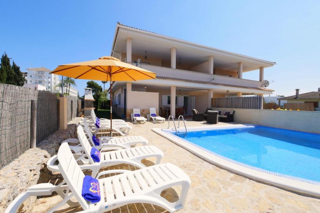 Eine Gruppe Stühle und ein Sonnenschirm neben einem Schwimmbecken in der Unterkunft Villa Jerónimo in Muro