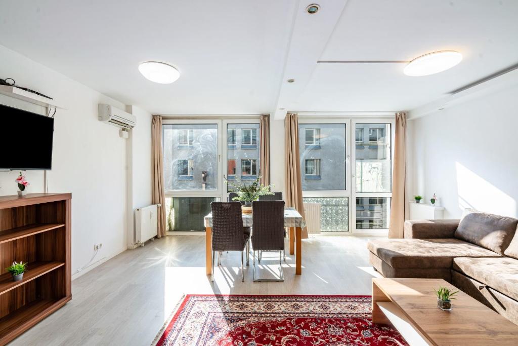 a living room with a couch and a table with chairs at Aldars Urban Trio Suite No.5 in Munich