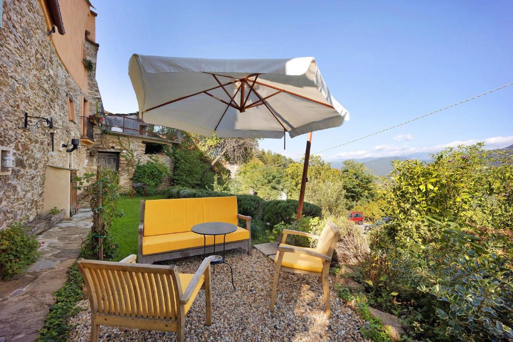 a patio with a table and an umbrella and chairs at Casa Vittorina in Cesio