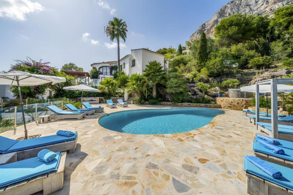 a swimming pool with blue chairs and a resort at Caroix in Jávea