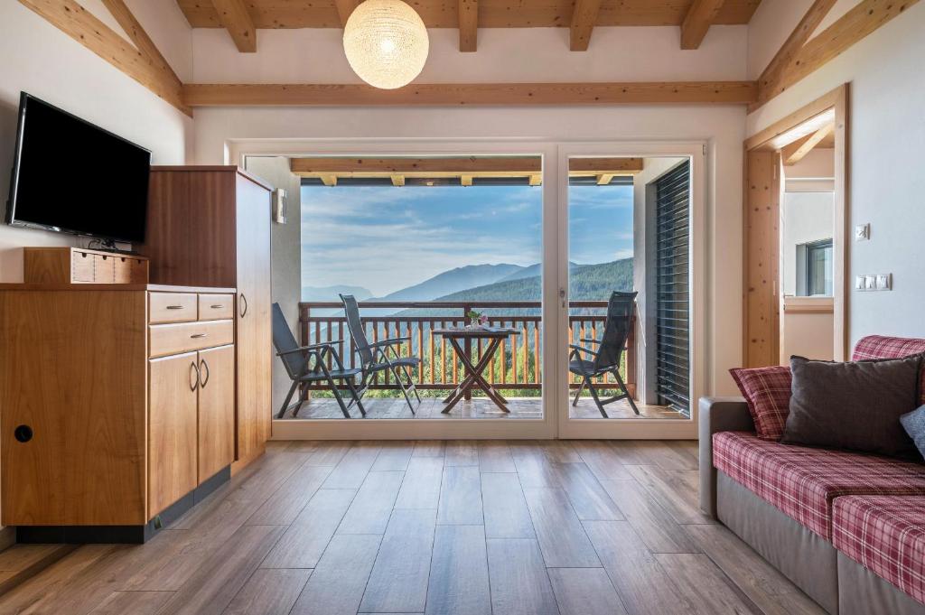 a living room with a couch and a tv and a balcony at Apt Gamsstube in Maranza