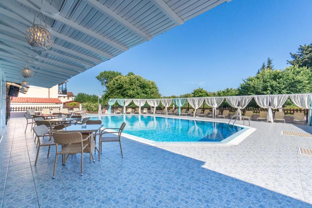 a patio with tables and chairs and a swimming pool at Saint Peter Bay - Basic Room in Kavos