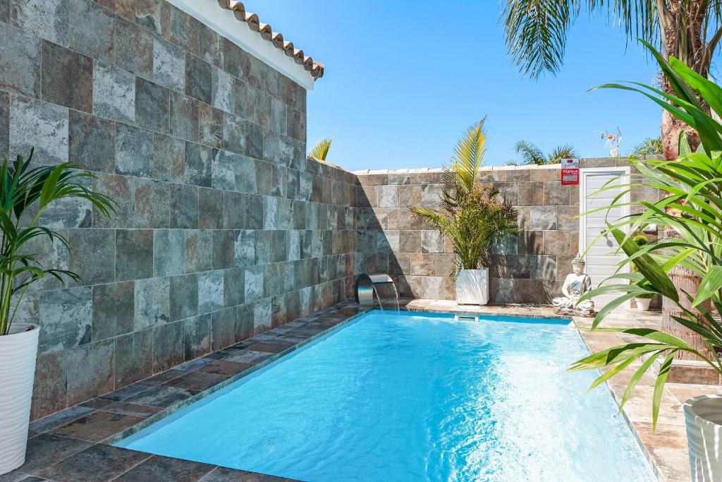 a swimming pool next to a stone retaining wall at Casa Bombón in Vejer de la Frontera
