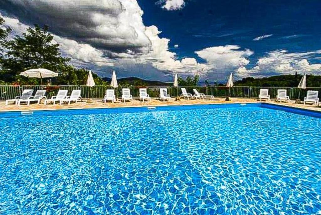 a large blue swimming pool with chairs and umbrellas at Mono Le Lecce 25 b in Capoliveri