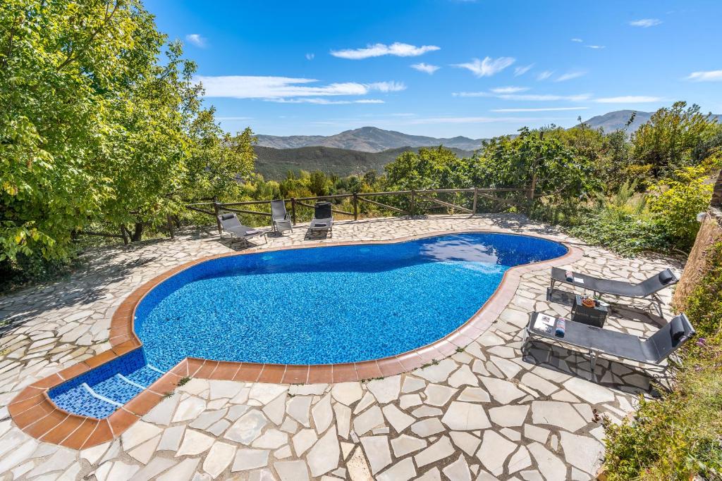 an image of a swimming pool in a backyard with chairs around it at Cortijo Jiménez in Pitres