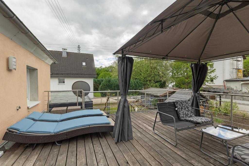 a patio with a bed and an umbrella on a deck at Casa Verde Sauerland in Lennestadt
