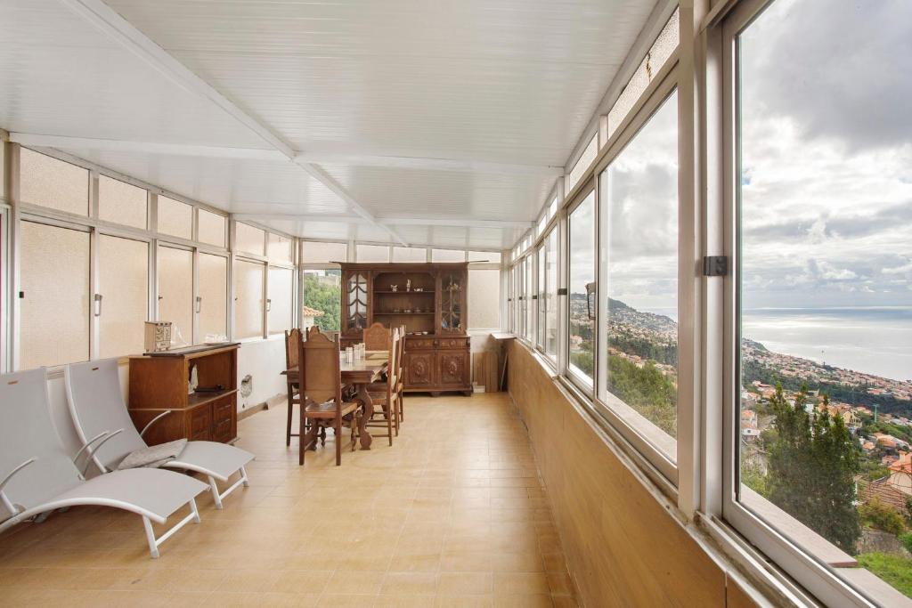 a room with large windows and a table and chairs at Carros De Cesto Do Monte in Funchal