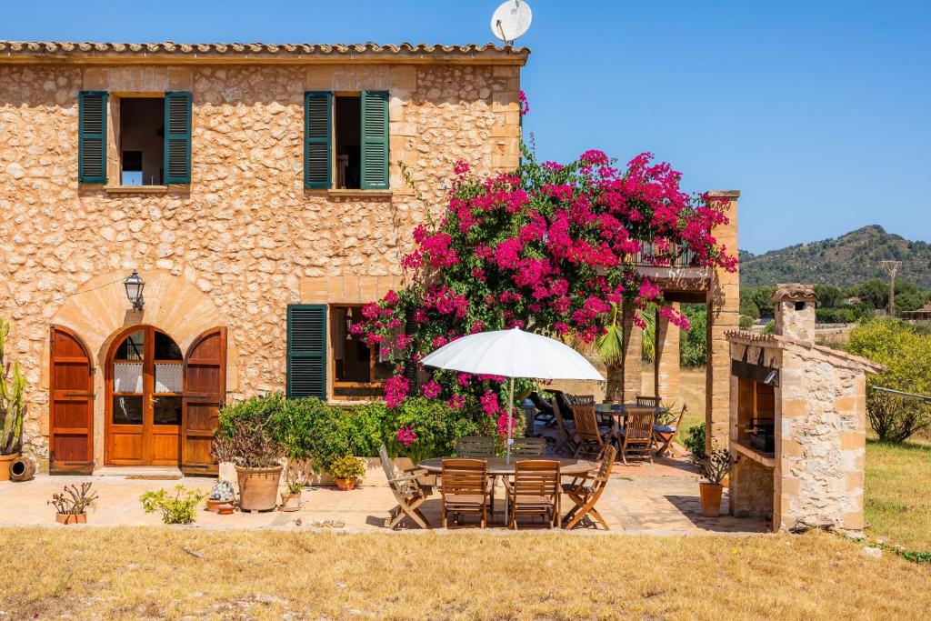 a stone house with a table and an umbrella at Can Carboneta in Artá
