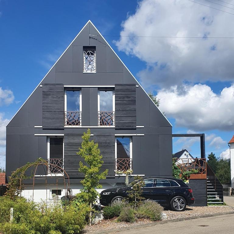 a gray house with a car parked in front of it at Alb - Lotte in Bitz