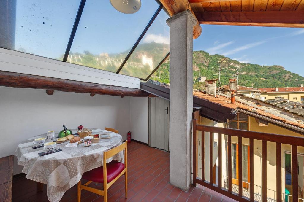 a room with a table and a balcony with a view at La Mansarda del Viaggiatore in Pont-Saint-Martin