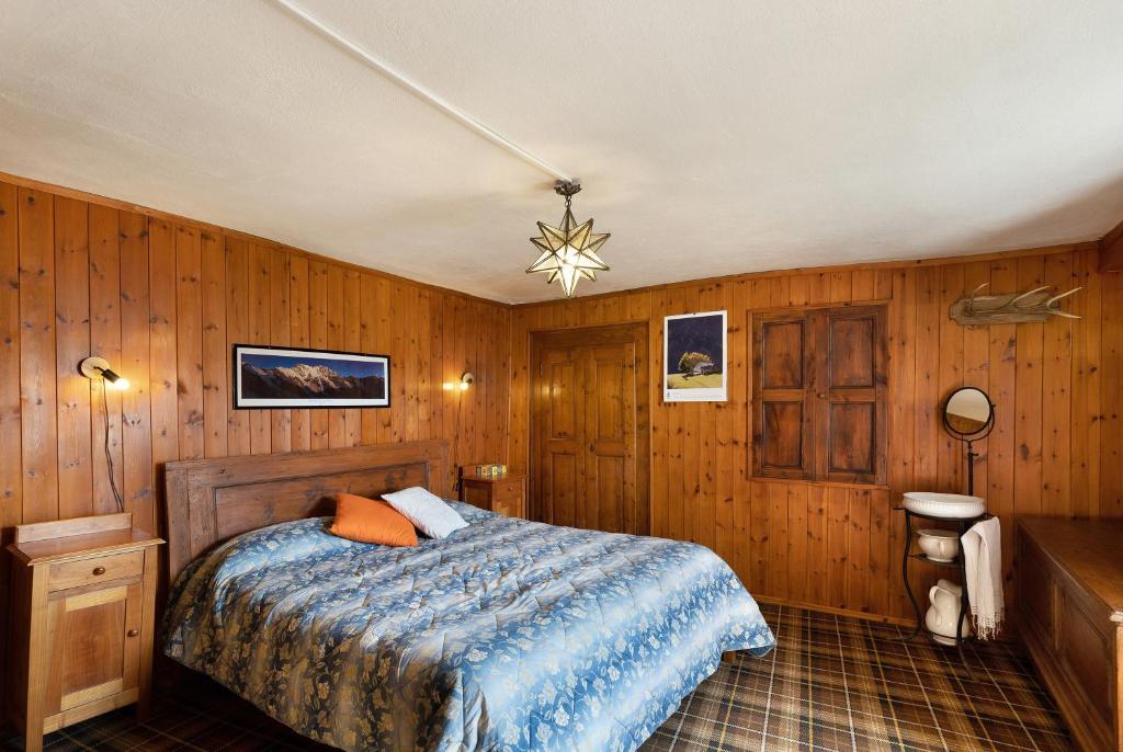 a bedroom with wooden walls and a bed with a blue blanket at Al Pinone in Crevoladossola
