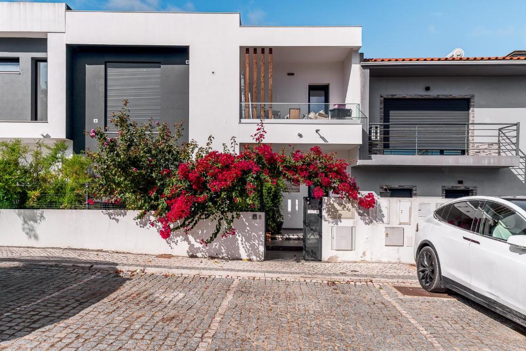 a white car parked in front of a house with flowers at Quarto do Papagaio in Palmela