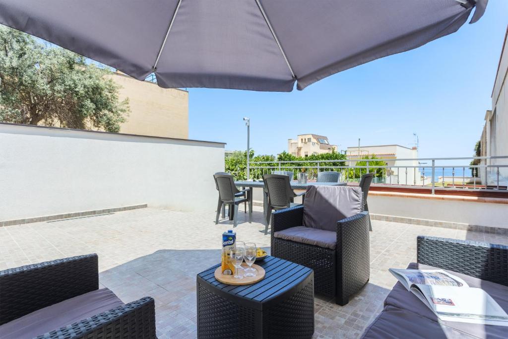 a patio with chairs and tables and an umbrella at Villa Mare Blu in Palermo