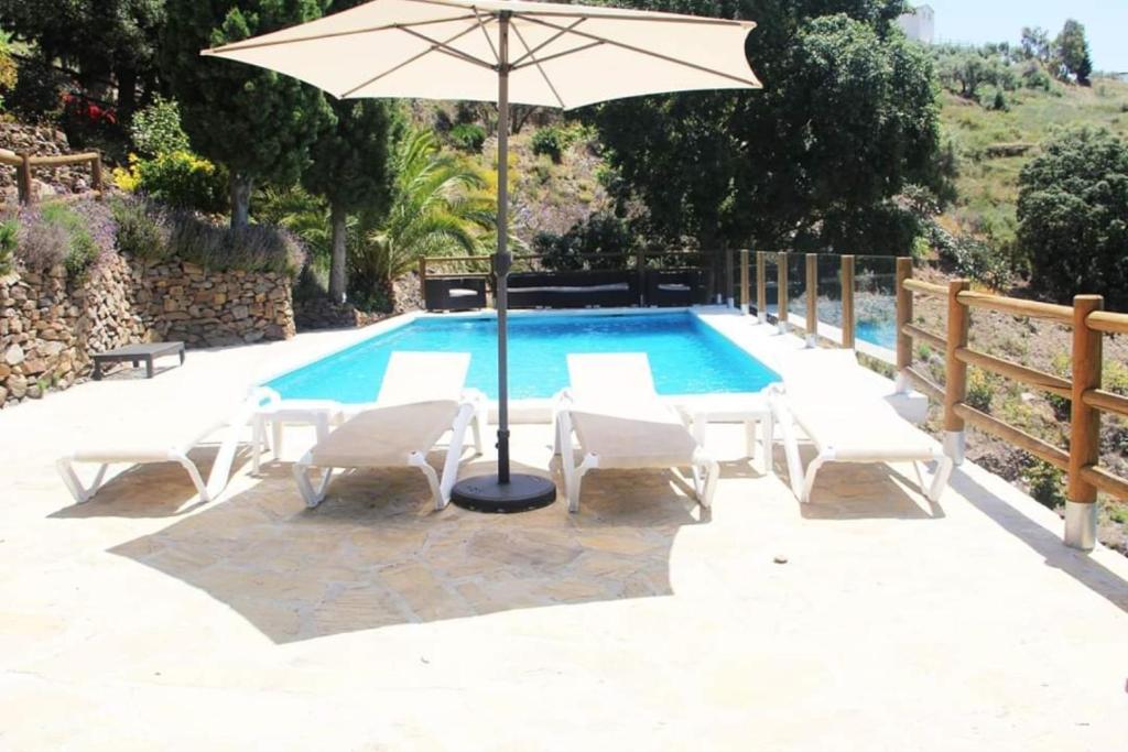 an umbrella and chairs and a swimming pool at Finca Colica in Cómpeta