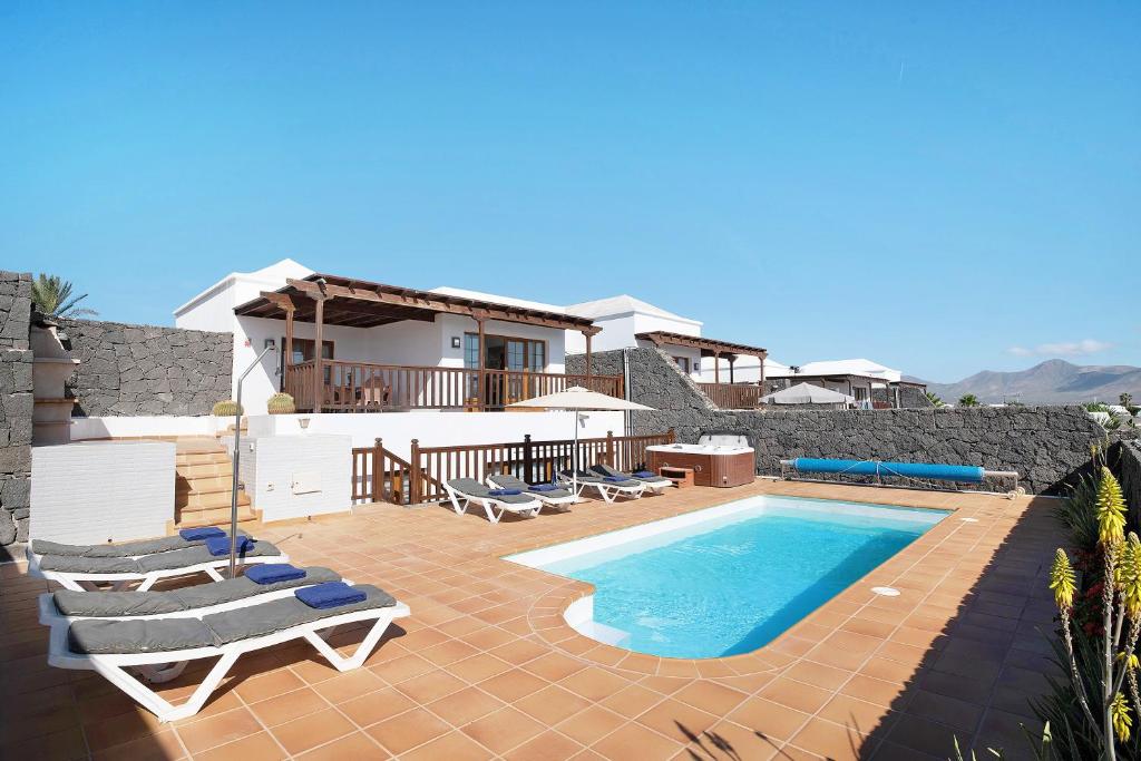 a swimming pool with lounge chairs and a house at Villa Jeamir I in Playa Blanca