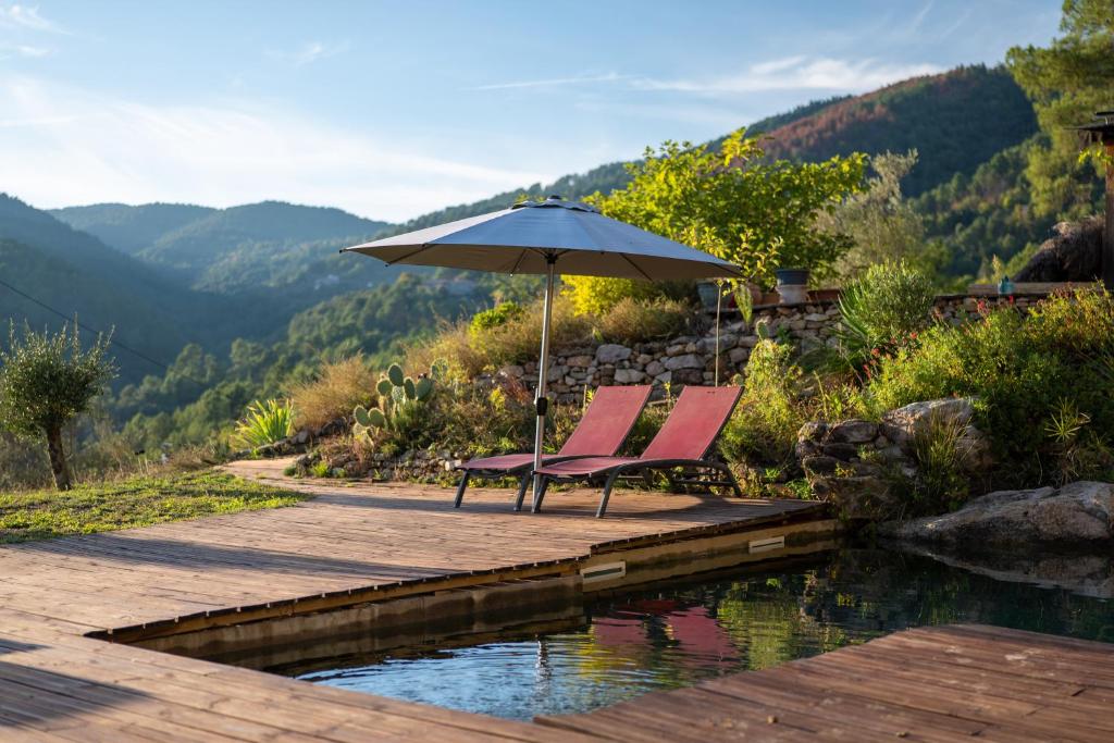 two chairs under an umbrella next to a pool at Gîte Écologique - Le Nid des Anges in Saint-André-Lachamp
