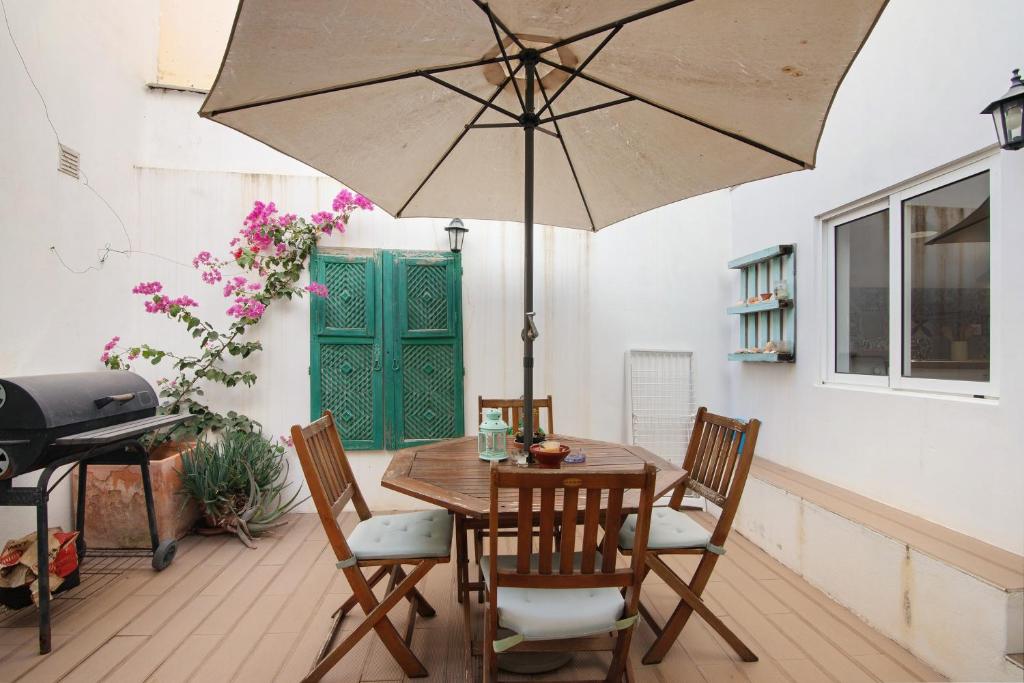 a wooden table with chairs and an umbrella at Casa Amarela in Tavira