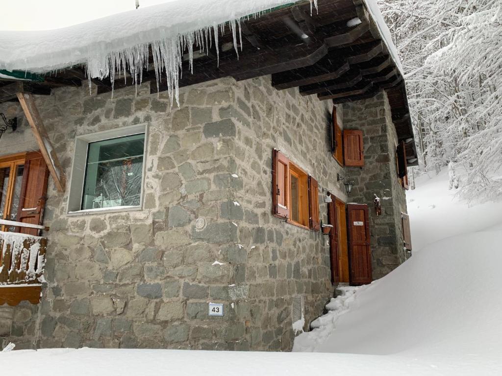a stone house with icicles hanging from it in the snow at Baita Le Pozze in Abetone