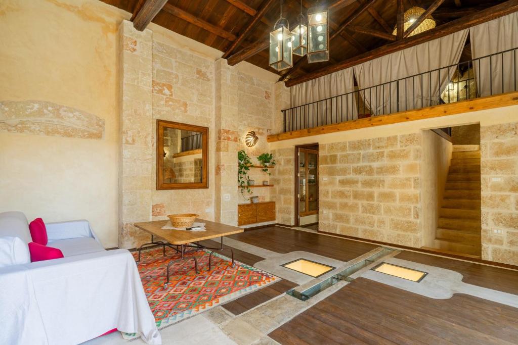 a living room with a table and a couch and a staircase at Dimora Pisanelli in Specchia