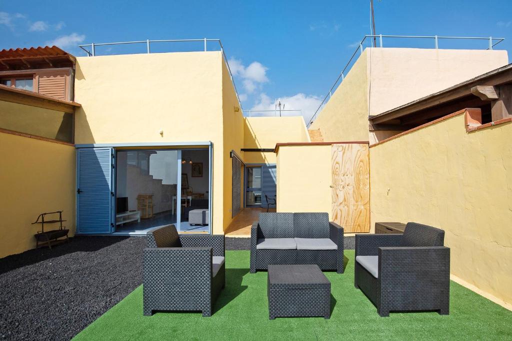 a patio with two chairs and a couch on grass at My Favorite Home in Caleta De Fuste
