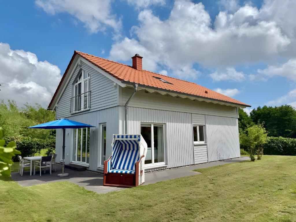 a house with a chair and a blue umbrella at Wildrosenhaus in Kosel