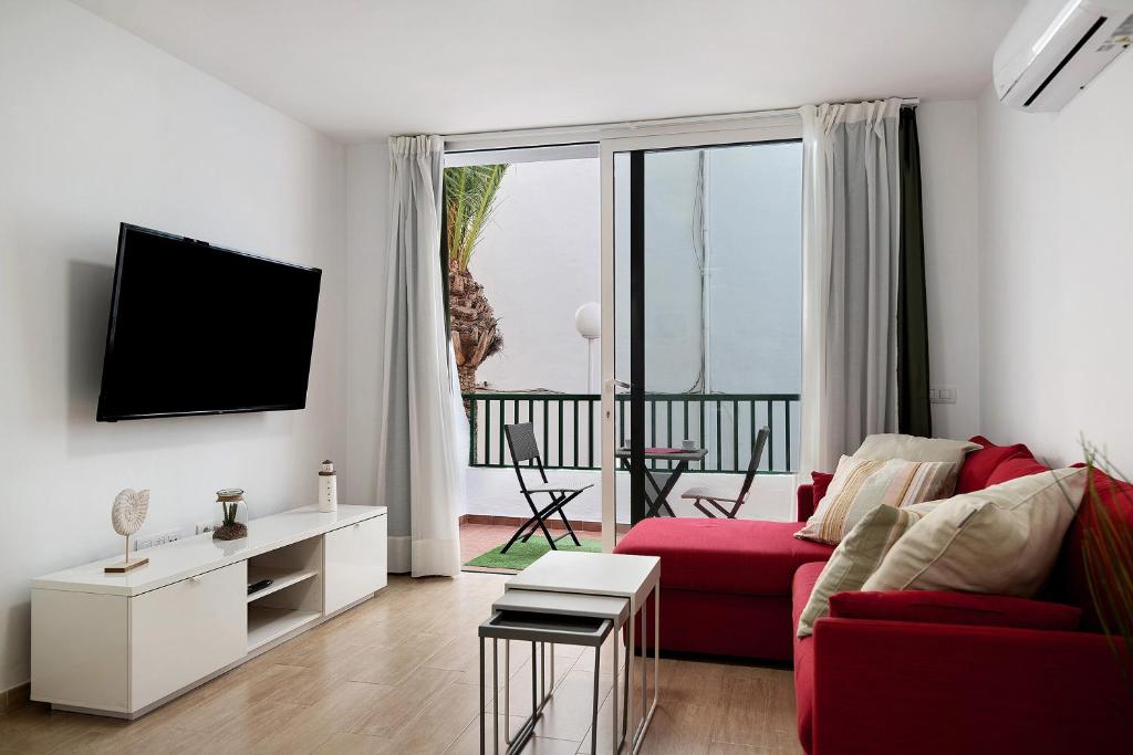 a living room with a red couch and a tv at Casa Joyne in Puerto del Carmen