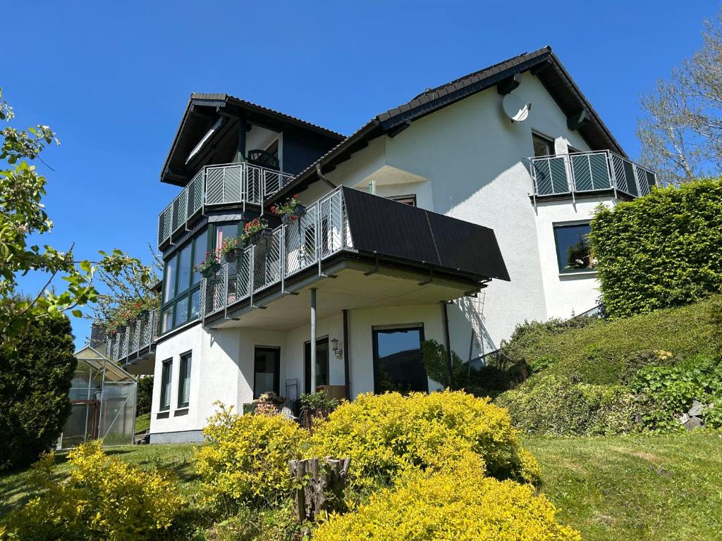 a white house with a balcony on a hill at Ferienwohnung Moos-Hochsauerland in Olsberg