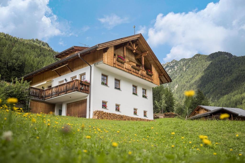 a house with a balcony on a hill with a field at Kuglerhof Apt 1 in Cadipietra