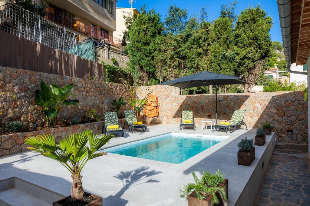 a pool with chairs and an umbrella next to a building at Villa Puerto in Sóller