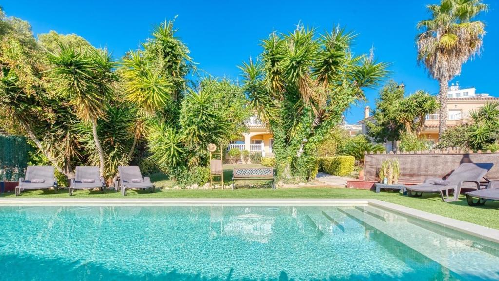 a swimming pool in front of a house with palm trees at Costacabana - Villa Summertime in Lloret de Mar