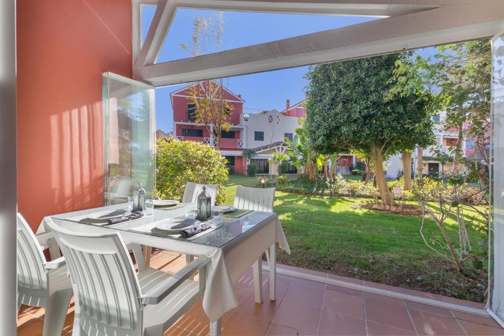 a dining room with a table and chairs and a large window at Duplex Islantilla Golf in Huelva