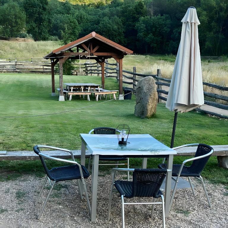 a table and chairs with an umbrella and a picnic shelter at El Albergue Rural in Mombeltrán