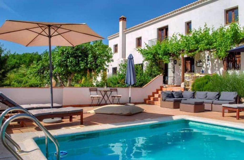 a house with a swimming pool and an umbrella at La Casa 1950 in Montefrío