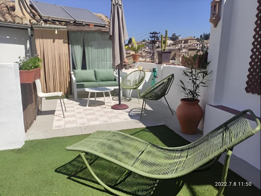 a patio with a green chair on a balcony at Casa con terraza centro Granada y vistas Alhambra in Granada