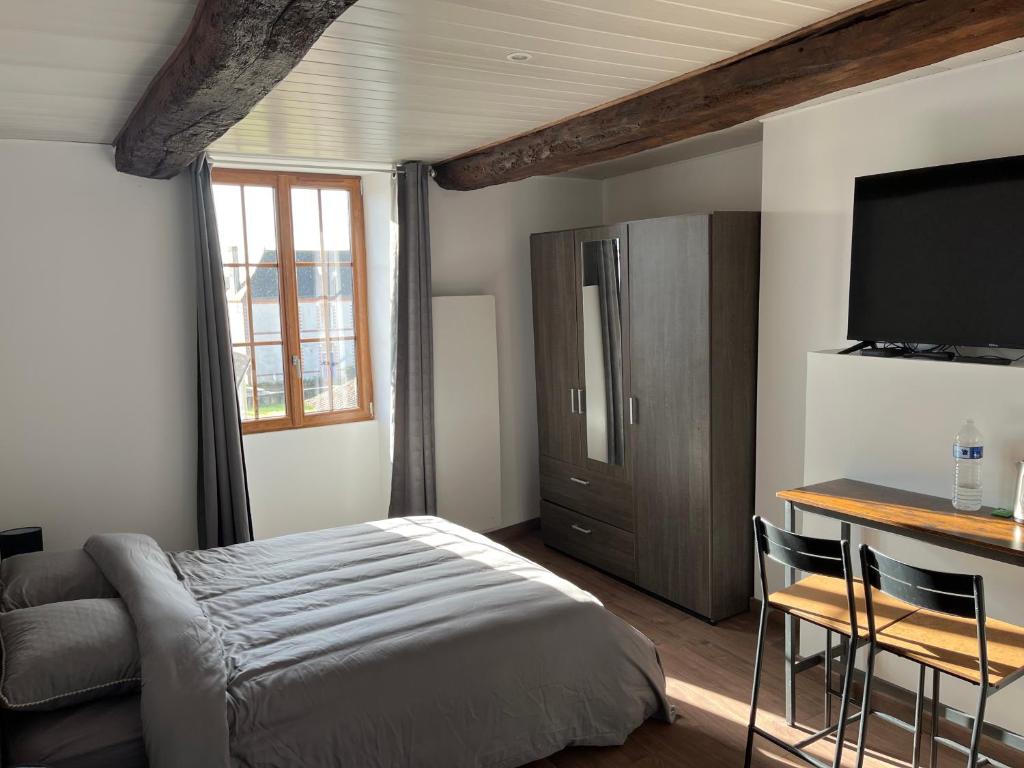 a bedroom with a bed and a desk and a television at Chambres d'hôtes Le Plessis in Frossay