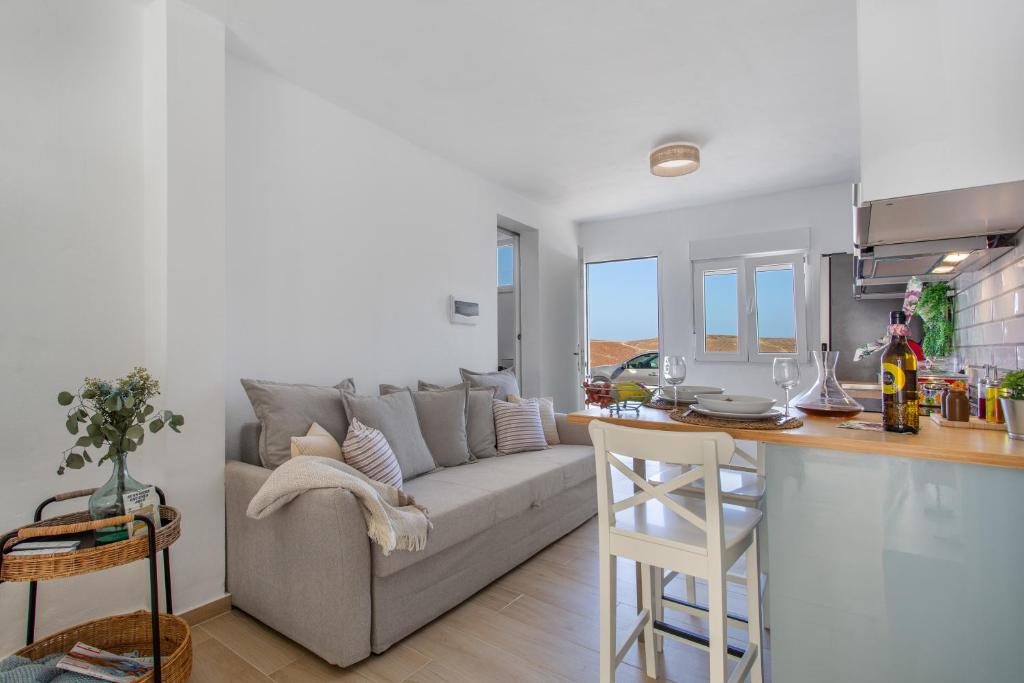 a living room with a gray couch and a kitchen at Neral relax in Las Playitas