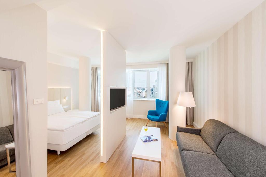 a living room with a couch and a bed at NH Collection Wien Zentrum in Vienna
