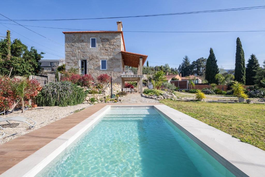 a villa with a swimming pool in front of a house at Casa Cándido in Ribarteme