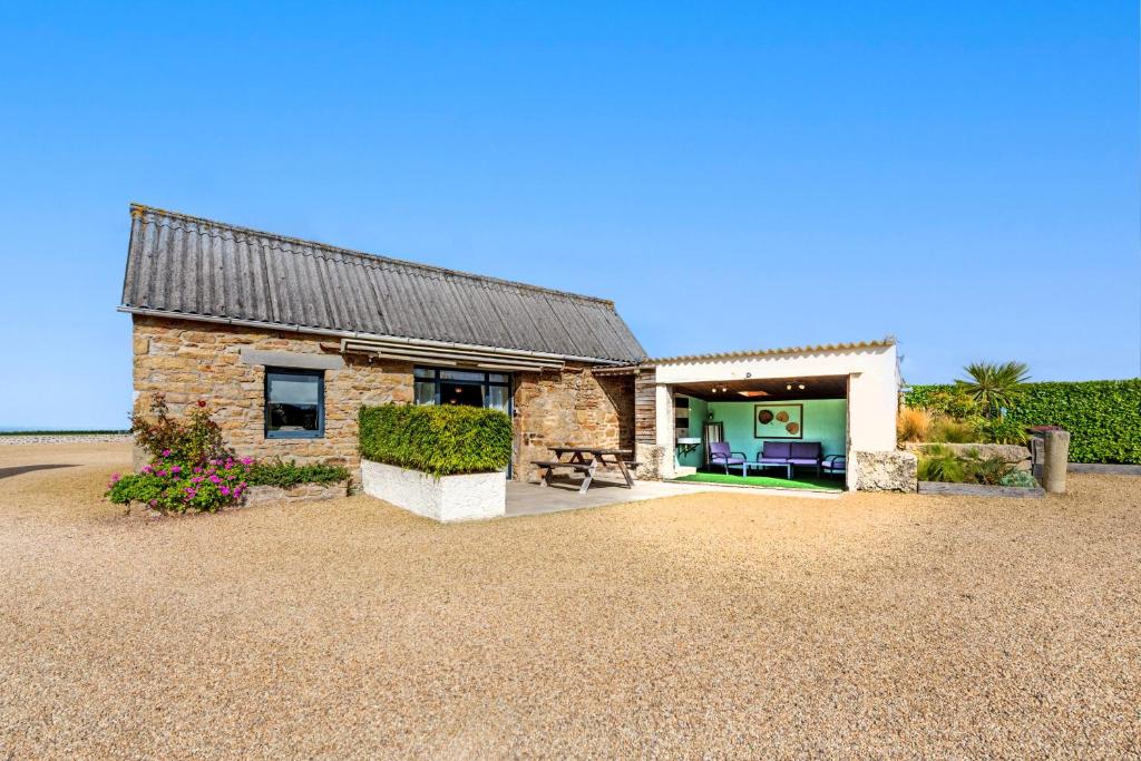 a brick house with a roof on a gravel driveway at Ty Reuniou - La Grange in Cléder